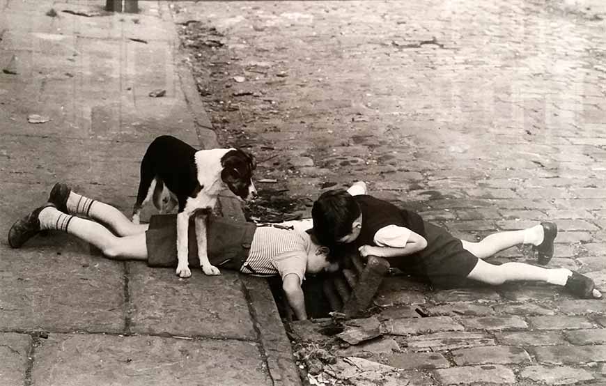 Two young boys peer down a drain (Пара мальчиков, всматривающихся в ливневый сток), 1963