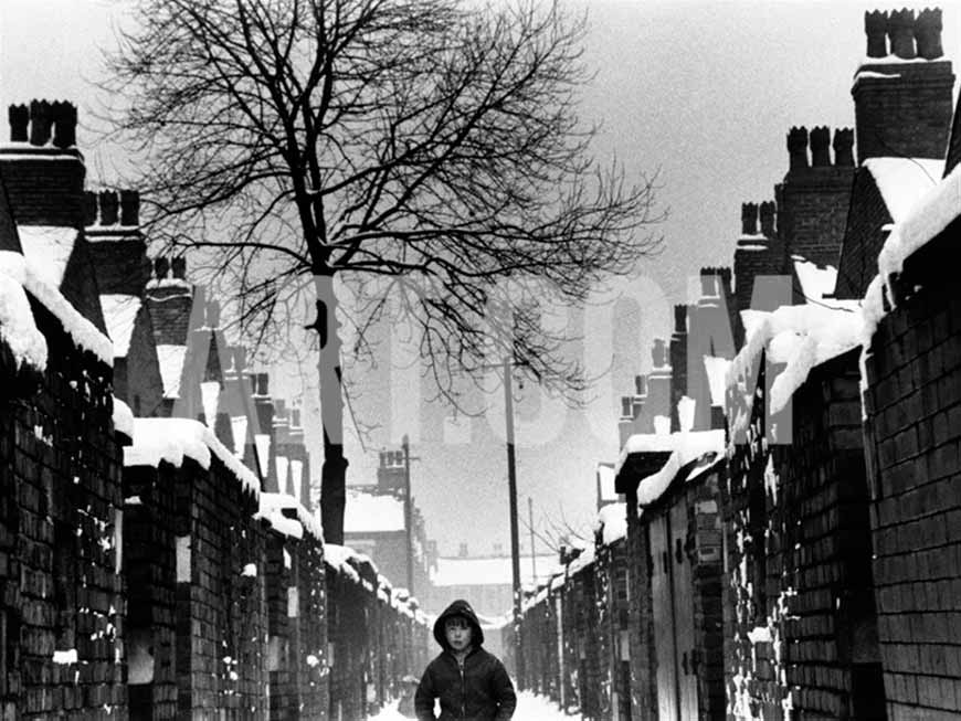 A boy in a jacket strolls down a rear passage alleyway between two rows of back to back terraced houses (Мальчик в куртке, прогуливающийся по переулку между двумя задними рядами таунхаусов), 1968