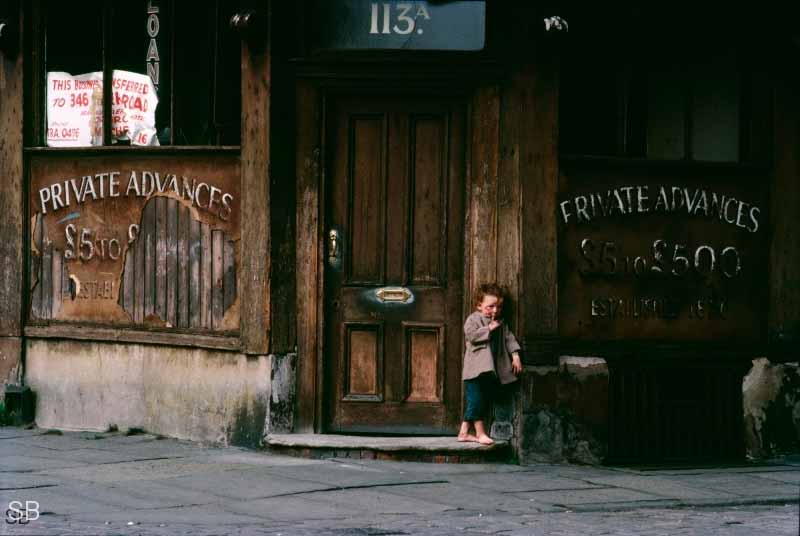 Scruffy little boy in a run-down shop doorway (Грязный мальчик у входа в захудалый магазин)