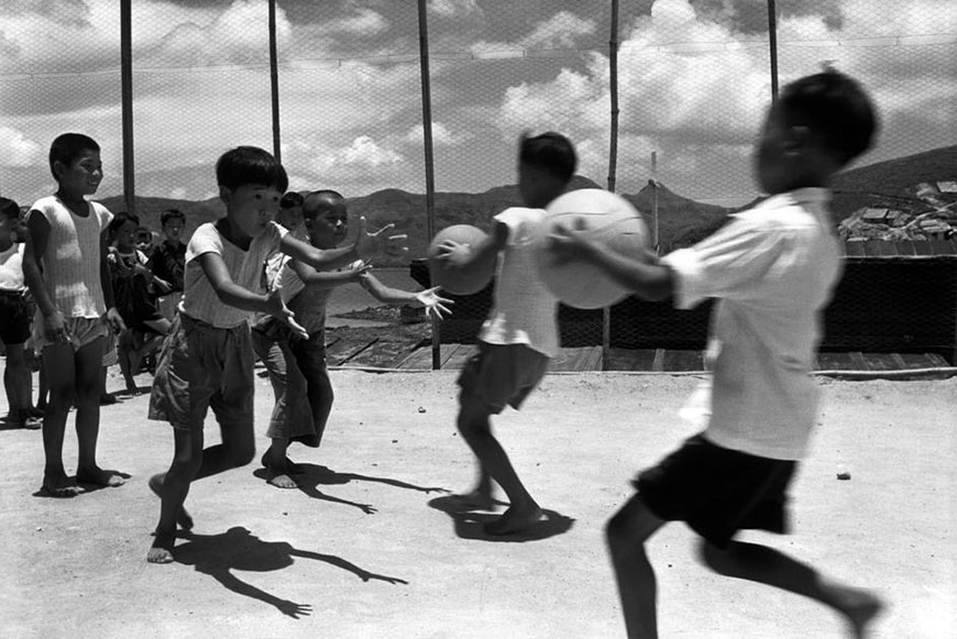 Children playing ball in fenced gameyard (Дети, играющие в мяч на огороженной площадке), 1952