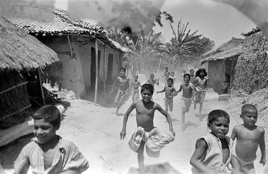 Children in a famine stricken area, running towards trucks delivering corn, 1951