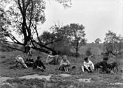 A group of young boys sitting on a riverbank getting dressed after a swim (Группа мальчиков сидит на берегу реки и одевается после купания), c.1900