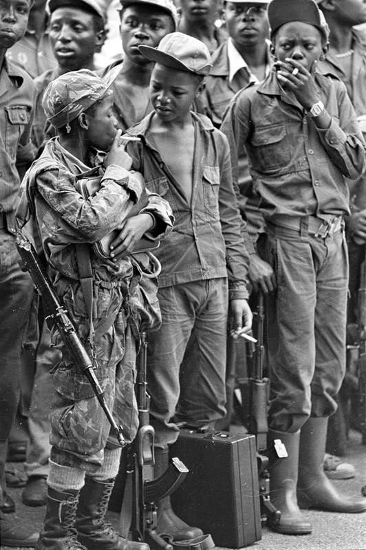 Child soldiers smoke as they watch the inauguration of Yoweri Museveni, National Resistance Army leader (Дети-солдаты курят, наблюдая за инаугурацией Йовери Мусевени, лидера Национальной армии сопротивления), 1986