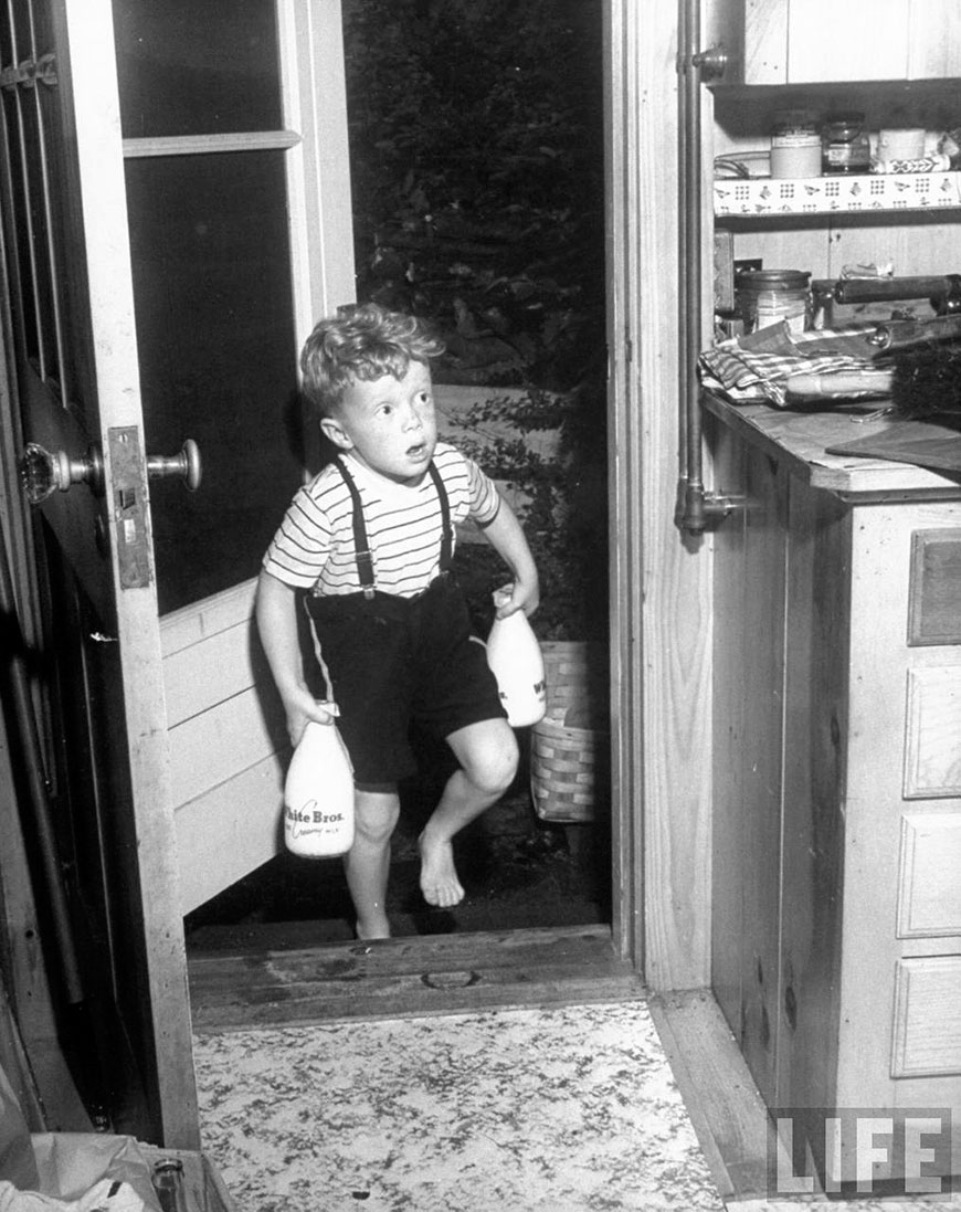 A little boy carrying the delivered milk bottles into the vacation house (Мальчик приносит молоко в домик для отдыха)