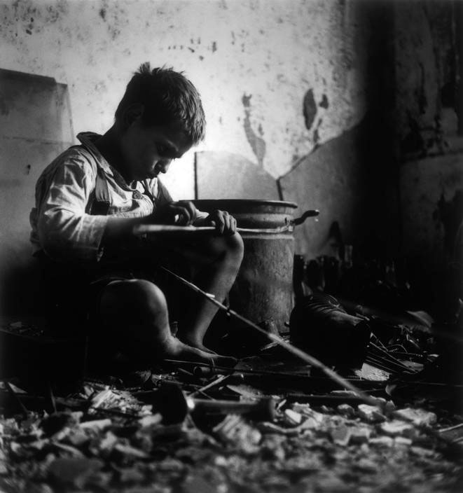 Playing in the attic of his house, damaged during the war, 1945