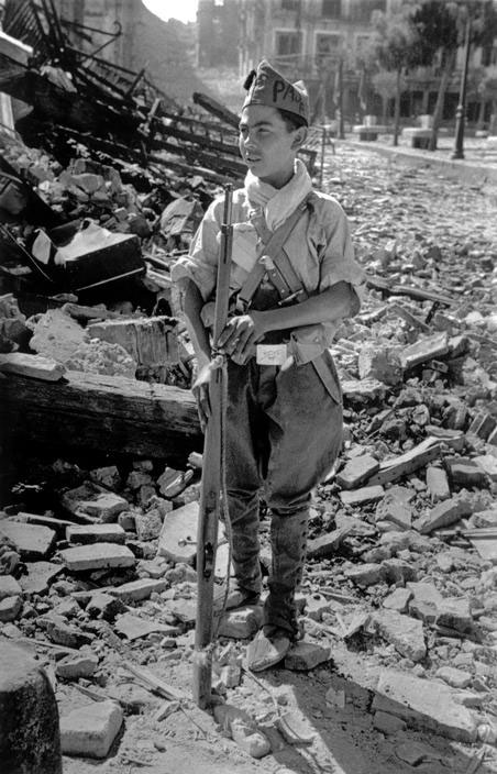 A young Communist militiaman standing near the ruins of the Alcazar (Юный коммунист-милиционер стоит у руин Альказара), 1936