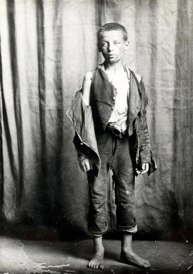 A young boy with torn clothes and a dirty face poses for a picture (Мальчик в рваной одежде и с грязным лицом позирует для фото), 1900