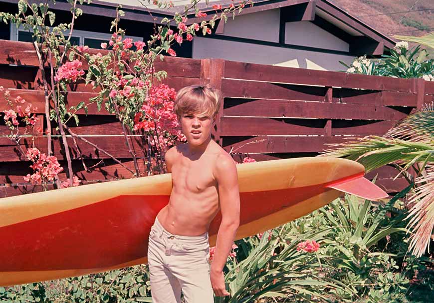 Kimo Uprichard poses in his Mokapu Boulevard backyard in Kailua before catching some waves (Кимо Упричард позирует позади Мукапу-Бульвара в Кайлуа перед тем, как ловить волны), 1965 