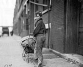 Boy Pushing Baby Carriage along Street / Мальчик с детской коляской на улице