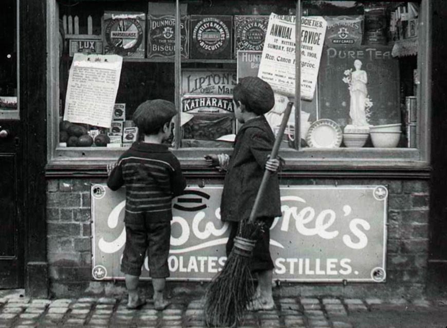 Two children looking at a window of a chocolate shop (Два ребенка заглядывают в витрину шоколадного магазина)