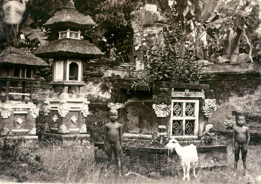 Twee Balinese jongens en een geit bij door struiken overwoekerde tempel en offerplaatsen bij Gianjar of Kloengkoeng (Два балийских мальчика и козел у храма и заросших кустарником мест жертвоприношений в Гьянджаре или Клоенгкёнге), 1900-1940s