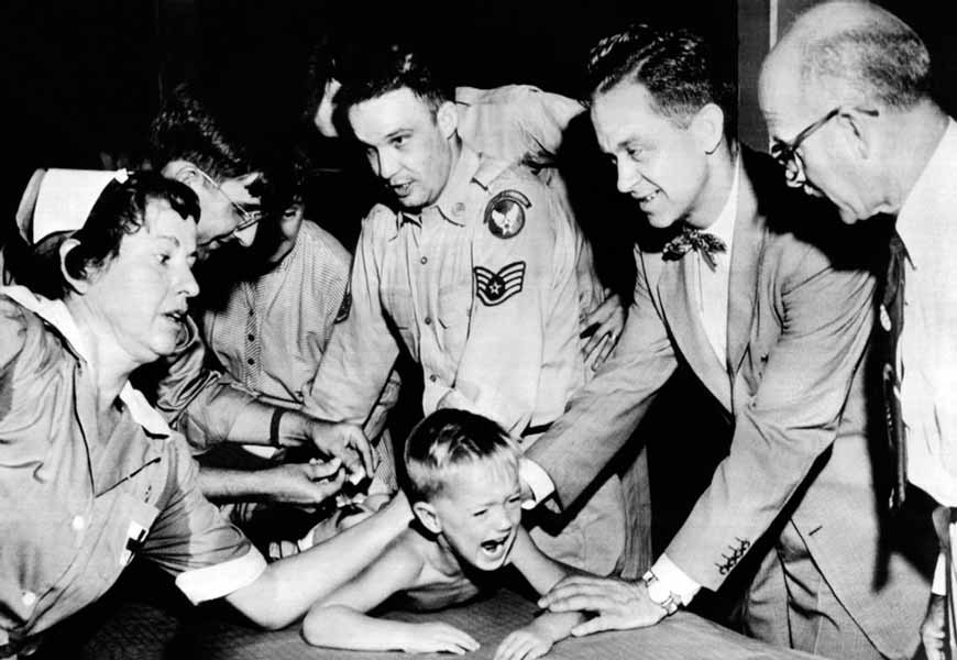 Several doctors and nurses restrain young Ernest Booth during polio vaccination (Несколько врачей и медсестер удерживают юного Эрнеста Бута во время вакцинации от полиомиелита), 1953