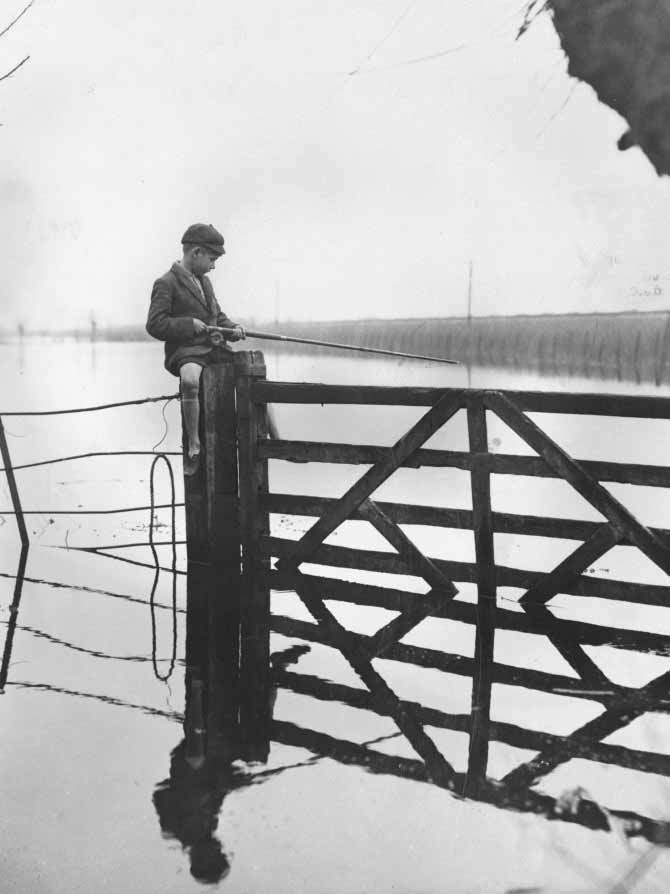 A young boy in his school uniform fishing from a gate near Langport (Мальчик в школьной форме, ловящий рыбу с ворот близ Лэнгпорта), 1935