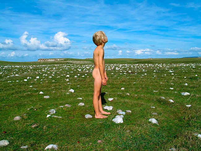 A nude boy standing in the middle of a spiral made of stones in the grass (Обнаженный мальчик, стоящий в траве посреди спирали из камней), 2001-2018