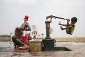 A boy collects drinking water from a hand pump / Мальчик качает питьевую воду ручным насосом