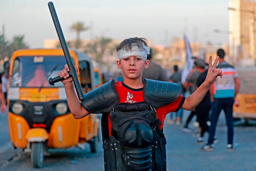 A boy poses for a picture amid clashes between supporters of Shiite Muslim cleric Moqtada and Iraqi security forces (Мальчик позирует фотографу на фоне столкновений между сторонниками шиитского священнослужителя Муктады и иракскими силами безопасности.), Sept. 2022