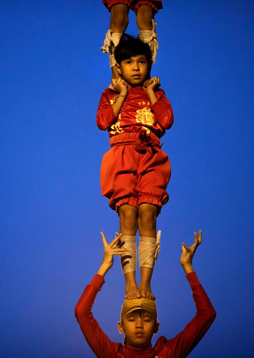 Young dancers of Look Chao Por Phra Kan Lion Dance troupe practice human pyramid acrobatic formation by during a dail​y training at an alleyway (Юные танцоры из труппы Look Chao Por Phra Kan Lion Dance отрабатывают человеческую пирамиду во время ежедневной тренировки в переулке), January 2021