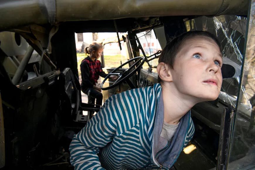 Boy Fadey from the village of Kolychovka plays in a wrecked military truck of the Russian army (Мальчик Фадей из села Колычовка играет в разбитом военном грузовике российской армии), апрель 2022