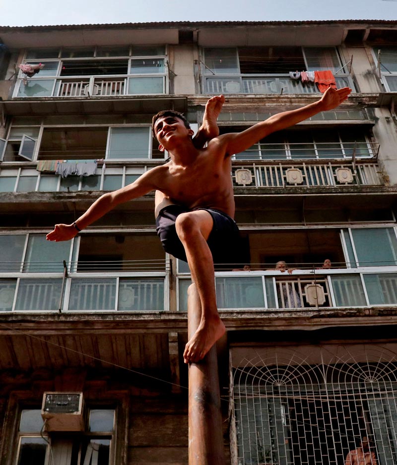 A boy performs 'Malkhamb' (traditional Indian gymnastics) during celebrations to mark the Gudi Padwa festival, the beginning of the New Year for Maharashtrians (Мальчик выполняет малкхамб (традиционную индийскую гимнастику) во время празднования фестиваля Гуди Падва-начала Нового года для жителей Махараштры), April 2022