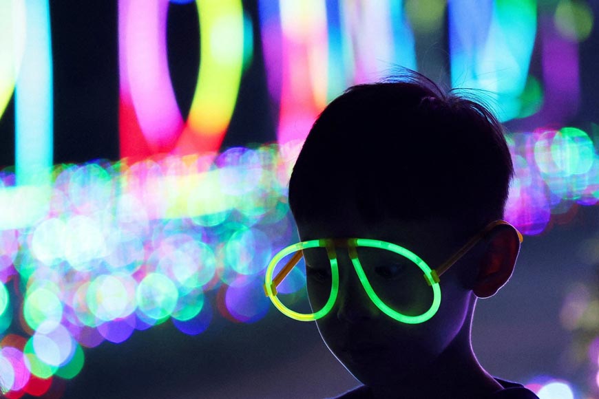 A boy wears glow stick glasses as he visits the Galactic Glow playground at Paris Van Java Resort Lifestyle Place (Мальчик в очках со светящейся оправой посещает игровую площадку Galactic Glow в Парис Ван Ява Ресорт Лавстайл Плэйс), 2024