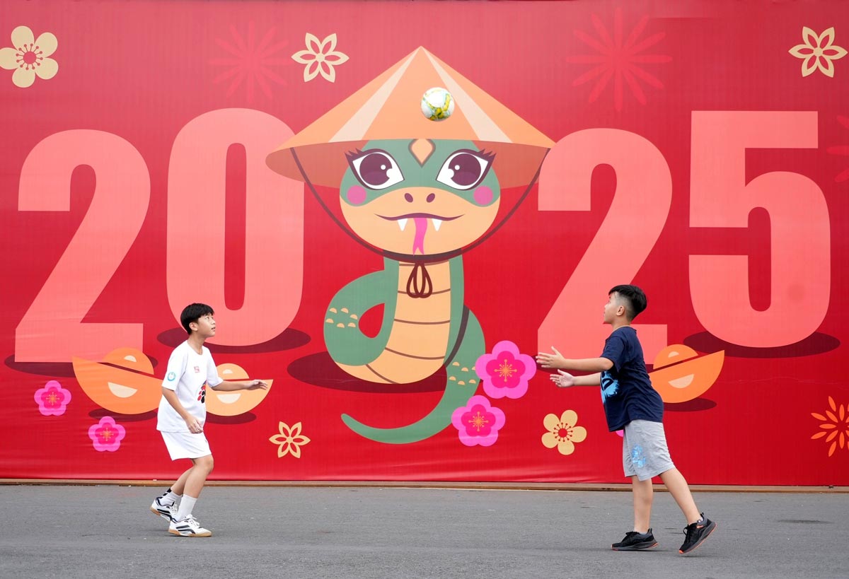 Two boys play football in front of a billboard welcoming the New Year 2025 (Двое мальчиков играют в футбол перед рекламным щитом, объявляющем Новый 2025 год), 2024