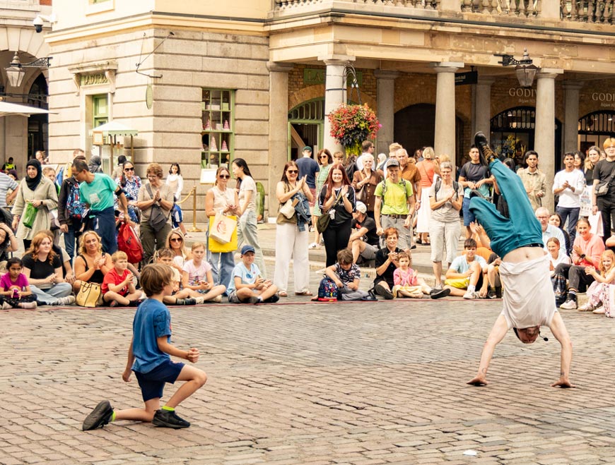 Street performer doing flips with a young boy as his volunteer (Уличный артист делает сальто, а добровольцем выступает мальчик), 2025