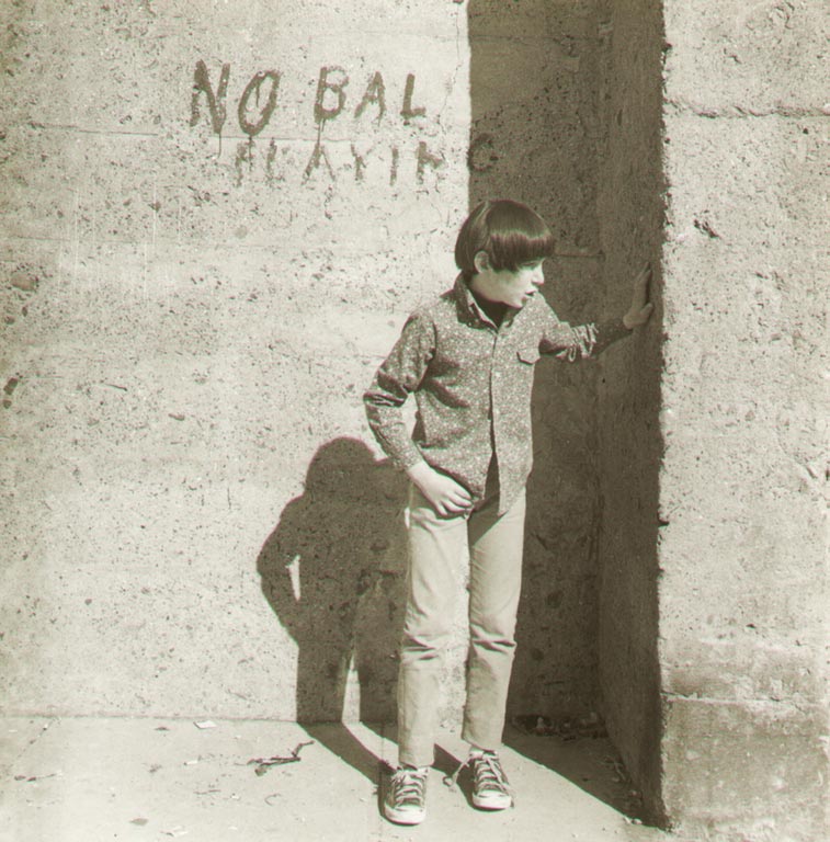 Boy in front of wall, graffiti no ball playing (Мальчик у стены с надписью "не играть в мяч")