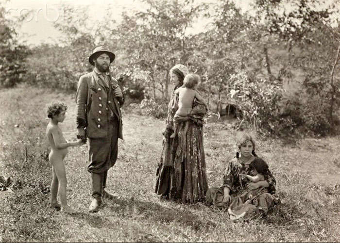 Gypsies relax in a field holding onto naked children (Отдыхающие в поле цыгане, держащие голых детей)