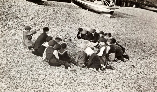 Children play at burying boys in rocks along Brighton's beach (Дети играют, засыпая мальчиков галькой на пляже Брайтона)