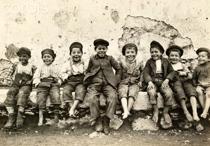 Italian boys sit and pose for the camera as they smile and laugh (Итальянские мальчики сидят и позируют камере, улыбаясь и смеясь)