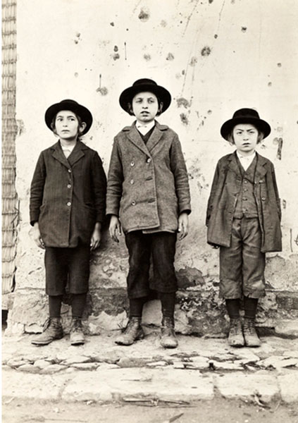 Three young Jewish boys stand for their picture along a wall (Три еврейских мальчика стоят у стены, позируя камере)