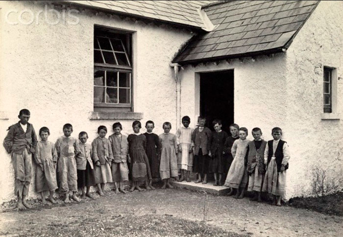 Barefoot and dressed in petticoats, schoolboys stand near school (Босиком, одетые в юбких, школьники стоят у школы), 1915