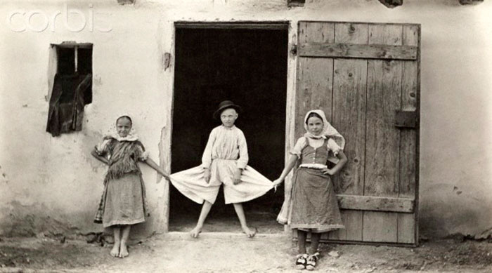 Girls stretch the cloth of a boy's trousers out to show the length (Девочки растягивают штаны мальчика, чтобы показать их ширину)