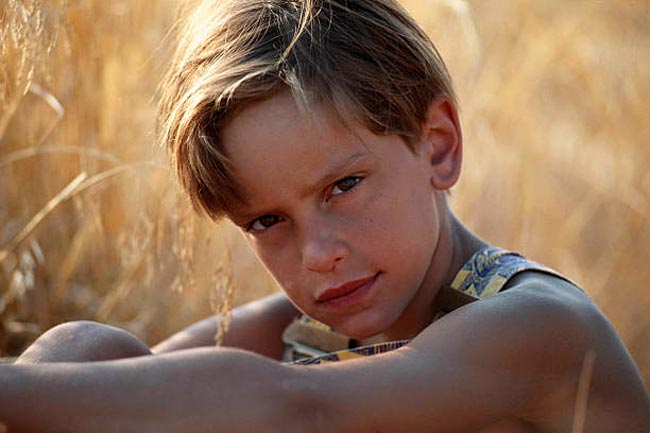 Boy in field, hugging knees (Мальчик в поле, обнимающий колени)