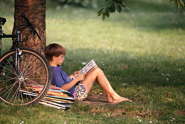 Boy leaning against tree, reading book (Мальчик, прислонившийся к дереву и читающий книгу)