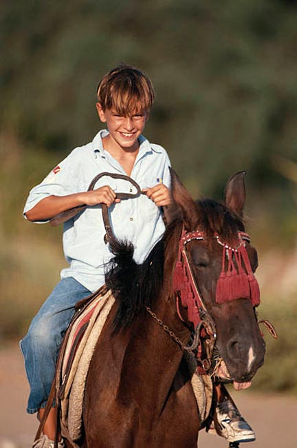 Boy riding horse, smiling (Улыбающийся мальчик на лошади)