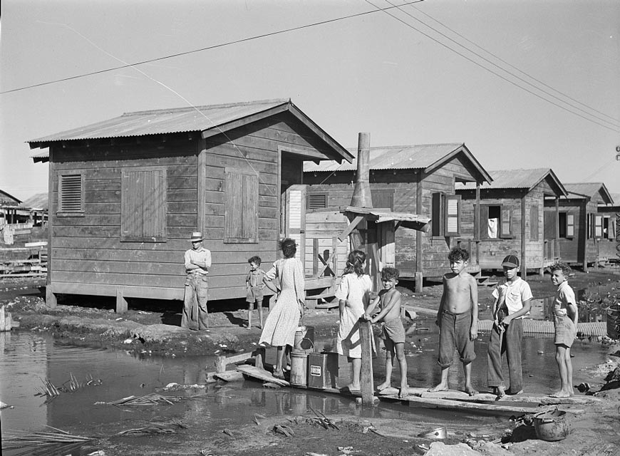 Fetching water from a spigot which services many people who live in the huge slum area known as 'El Fangitto' (Набор воды из крана, обслуживающего многих людей, живущих в огромных трущобах, известных как «Эль Фангитто»), Jan. 1942 