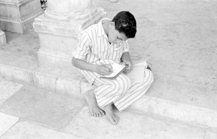 Boy sitting against base of column writing in book (Мальчик, сидящий у подножия колонны и записывающий в книгу), 1950-1960s