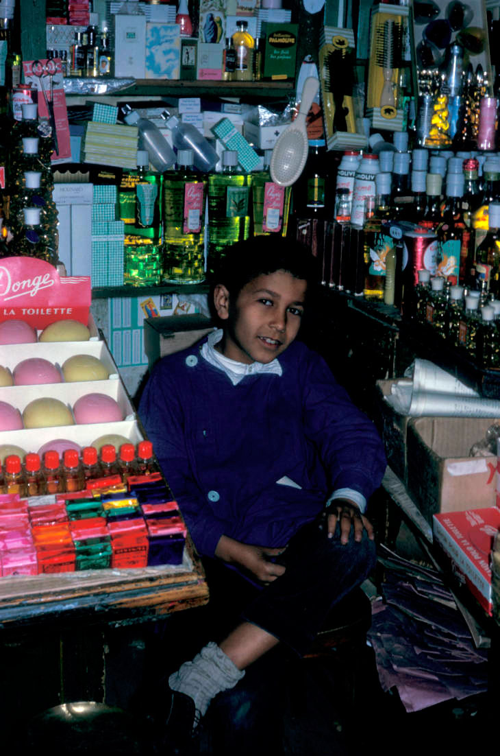 Boy seated between shelves of store merchandise (Мальчик, сидящий между полками магазина), 1968