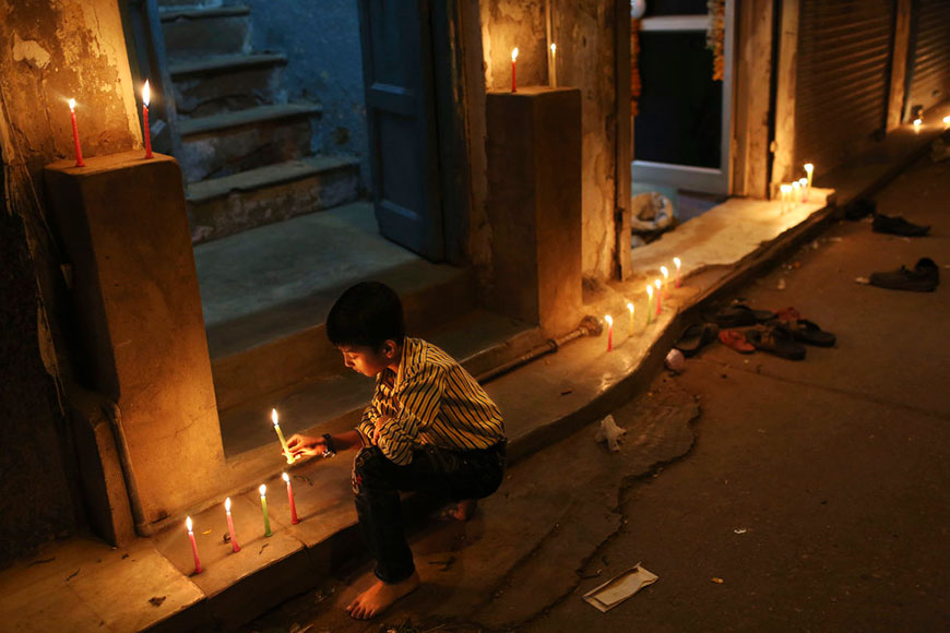 An Indian boy lights candles in front of his family's business during the festival of Diwali (Индийский мальчик зажигает свечи перед лавкой своей семьи во время фестиваля Дивали), Nov.13.2012