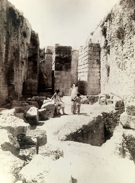 Boys draped in Roman era tunics stand in stone ruins (Мальчики в римских туниках стоят у каменных руин)