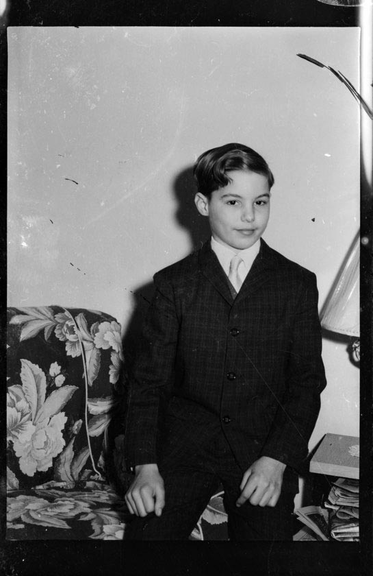 Portrait of boy wearing plaid suit and light colored tie, seated on arm of floral sofa or chair (Портрет мальчика в клетчатом костюме и светлом галстуке, сидящего на подлокотнике цветастого дивана или стула), 1962