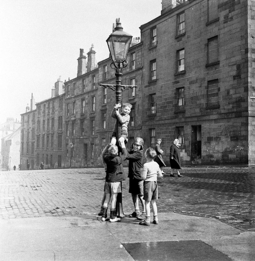 A group of boys help a companion climb a lamppost in a Glasgow street (Группа мальчиков помогает товарищу забраться на фонарный столб на улице Глазго), 1955 