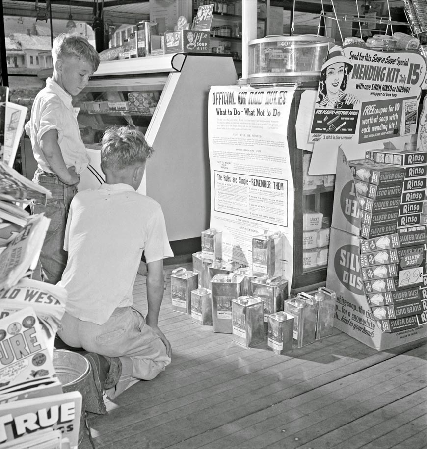 Maynard Clark[14] and Guy Davenport[11] reading the air raid instructions posted in Gilbert S. Hastings's post office and general store (Мейнард Кларк[14] и Гай Дэвенпорт[11] читают инструкции по воздушной тревоге, размещенные в почтовом отделении и магазине Гилберта С. Гастингса), 1942 