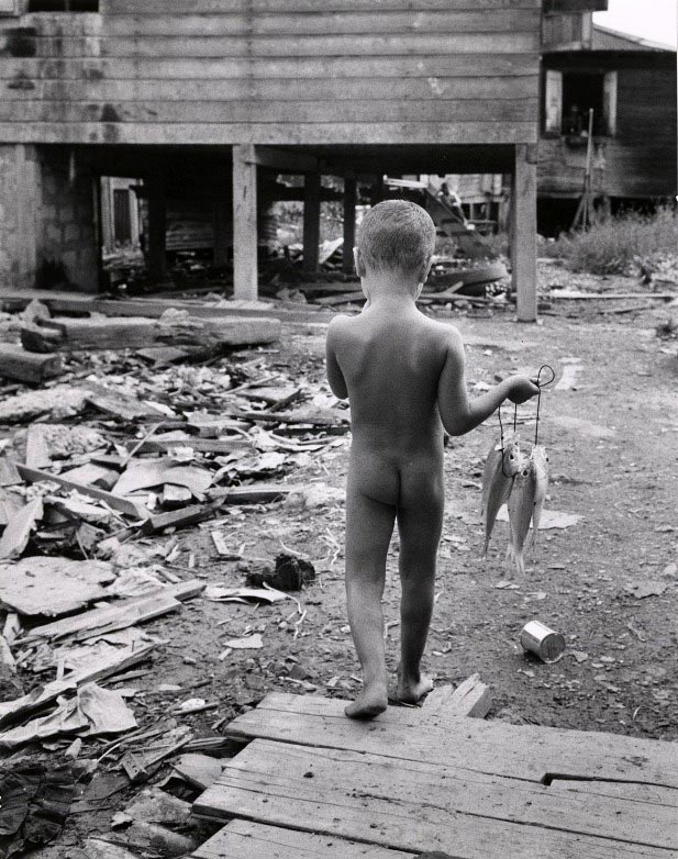 Unclothed boy carrying fish walking through debris (Раздетый мальчик, несущий рыбу, идущий по обломкам), 1964