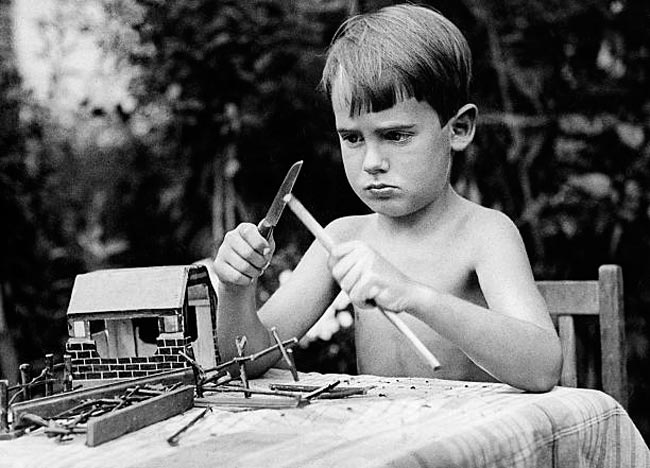 A boy tinkers a wooden house with a knife (Мальчик чинит ножом деревянный домик), 1932