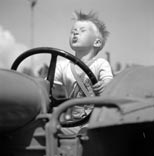 Маленький мальчик, сидящий в кабине трактора