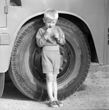 Мальчик, опирающийся на автомобильную шину