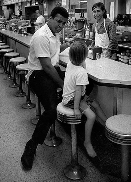 Muhammad Ali with young fan in diner (Мухаммед Али обедает со своим фанатом), 1970