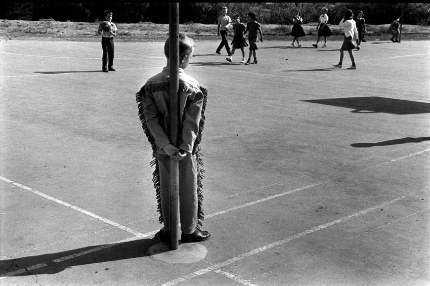 A boy stands alone, leaning against a pole, watching others on the playground (Мальчик, стоящий в одиночестве, прислонившись к столбу, и наблюдая за другими на игровой площадке), 1958